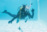 Woman on scuba training submerged in swimming pool making ok sign