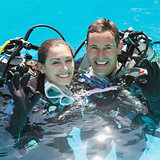 Smiling couple on scuba training in swimming pool showing ok gesture