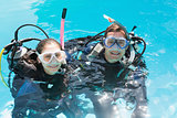 Smiling couple on scuba training in swimming pool looking at camera