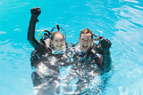 Smiling couple on scuba training in swimming pool looking at camera