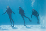 Three friends on scuba training submerged in swimming pool