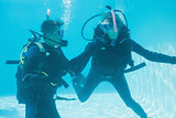 Friends on scuba training submerged in swimming pool