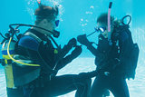 Man proposing marriage to his shocked girlfriend underwater in scuba gear