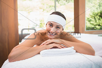 Beautiful smiling brunette lying on massage table