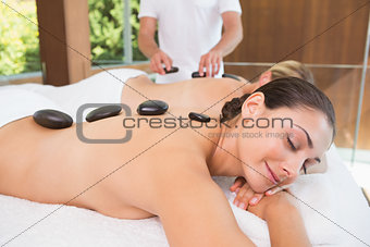 Happy friends lying on massage tables with hot stones on their backs