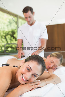 Pretty friends lying on massage tables getting hot stone massages