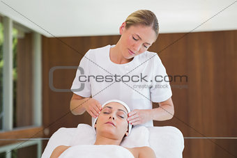 Peaceful brunette getting facial massage from beauty therapist
