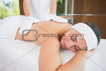 Beauty therapist rubbing womans back with heated mitts