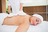 Beauty therapist rubbing womans back with heated mitts