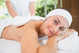 Beauty therapist rubbing smiling womans back with heated mitts