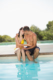 Gorgeous couple sitting poolside on holidays