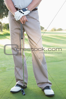 Lower half of golfer standing with club