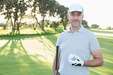 Handsome golfer standing with golf ball