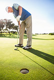 Golfer standing on the putting green watching hole