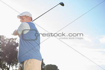 Golfer standing and swinging his club
