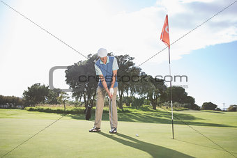 Golfer putting ball on the green