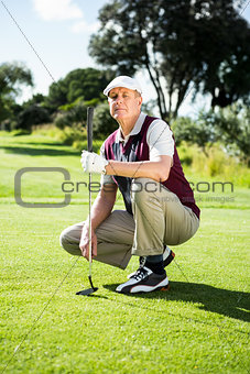 Golfer kneeling holding his golf club