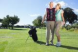 Golfing couple standing smiling at each other