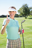 Female golfer standing and pointing up