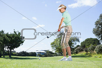 Female concentrating golfer teeing off