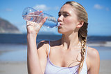 Focused fit blonde drinking water on the beach