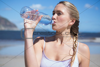 Focused fit blonde drinking water on the beach