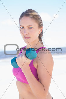 Fit woman working out with dumbbells on the beach