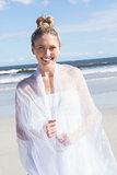 Pretty blonde wrapped in white shawl on the beach