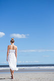 Blonde in white dress walking on the beach