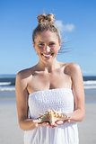 Pretty blonde in white dress holding starfish on the beach
