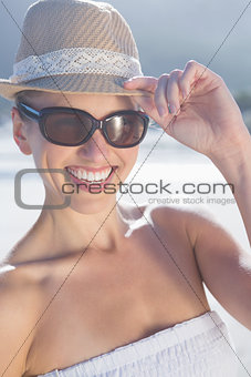Pretty blonde in white dress and sunhat on the beach