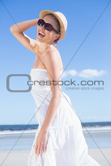 Pretty blonde in white dress and sunhat on the beach