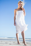 Blonde in white dress smiling at camera on the beach