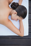 Peaceful brunette lying poolside on towel