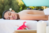 Smiling brunette lying on towel having a hot stone massage