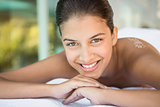 Smiling brunette lying on towel looking at camera