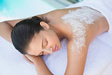 Calm brunette lying on towel with salt treatment on back