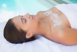 Calm brunette lying on towel with salt treatment on chest