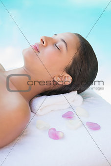 Calm brunette lying on towel with rose petals