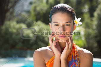 Brunette in sarong looking at camera by the pool