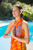 Brunette in sarong meditating by the pool