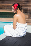 Beautiful brunette in towel sitting by the pool
