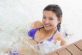 Smiling brunette in bikini relaxing in hot tub