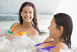 Smiling friends in bikinis relaxing in hot tub