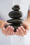 Beauty therapist holding pile of stones for massage