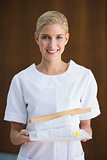 Smiling beauty therapist holding white towels