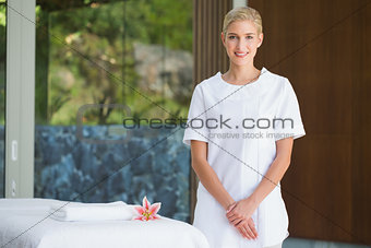 Smiling beauty therapist standing beside massage towel