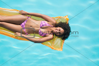 Happy woman lying on lilo in swimming pool