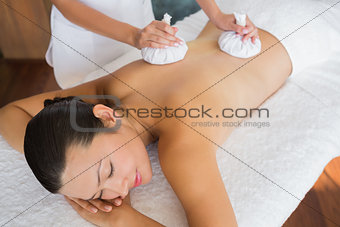 Content brunette getting a herbal compress massage