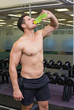 Shirtless bodybuilder drinking sports drink